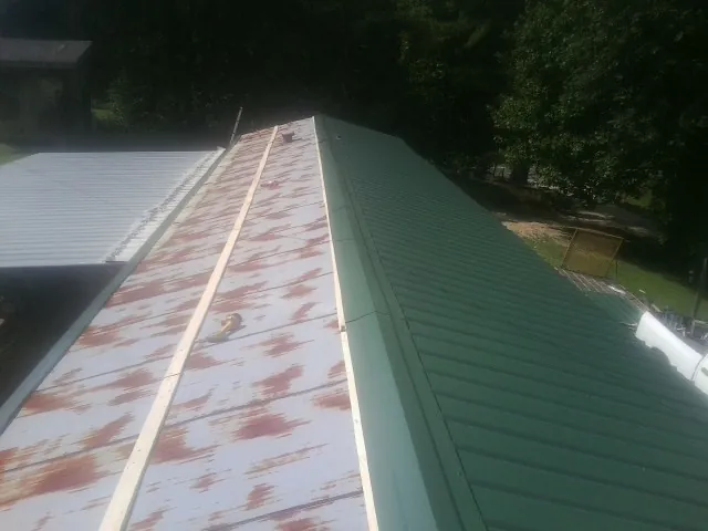 Old rusted panels beside newly installed green metal roofing — Wind Damage Roof Repair by Roofing Brothers in Indian Trail
