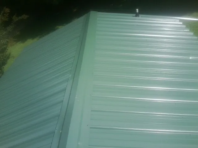 New green metal panels meeting at the ridge of a roof — Flat Roof Repair work by our crew in Indian Trail