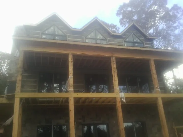 Dormers and porch framing on a large log home under construction — Roof Coating work by our crew in Indian Trail