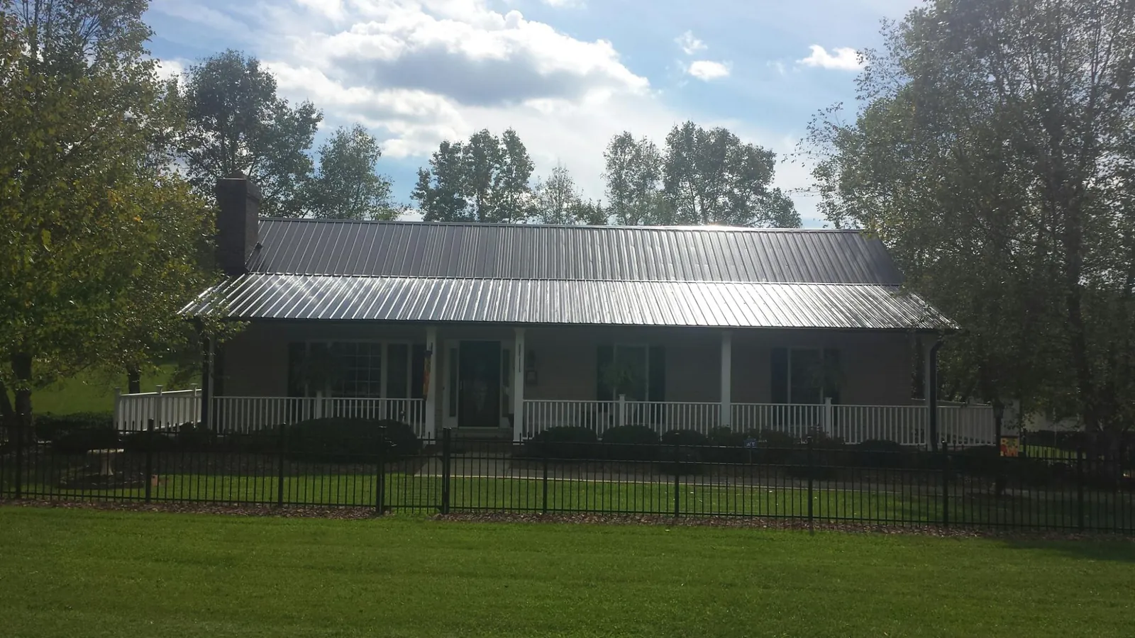 Gray metal roof on a brick ranch with a full width front porch — Gutter Guard Installation work by our crew in Indian Trail