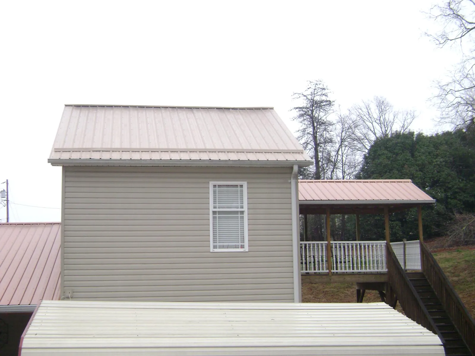 Tan metal roofs on a two story addition and attached porch, from a Roof Replacement job in Indian Trail