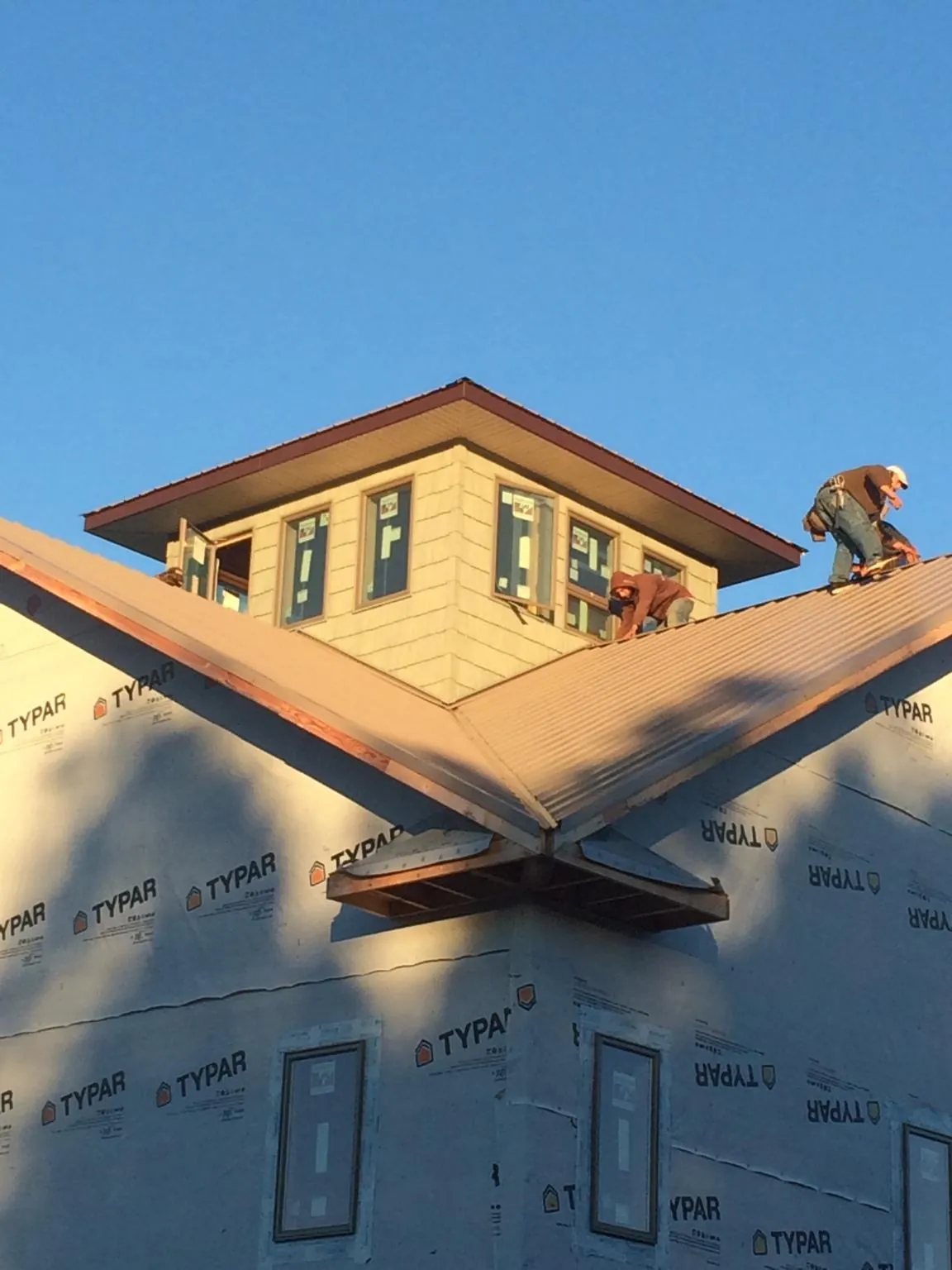 Roofers working around a rooftop cupola on a new metal roof at sunset — Roof Waterproofing in Indian Trail by Roofing Brothers